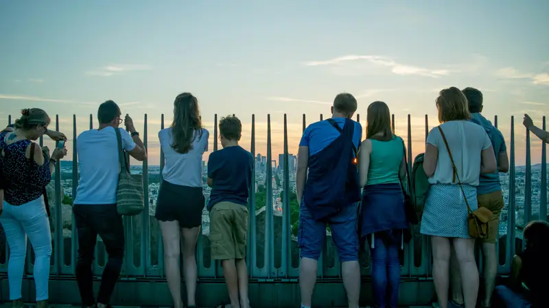 Visitors at a city viewpoint railing looking out over the skyline