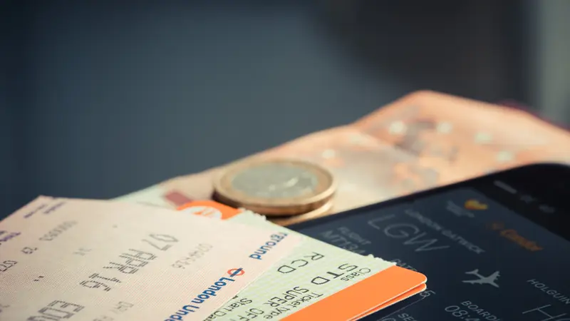 Printed travel tickets and a coin on a table