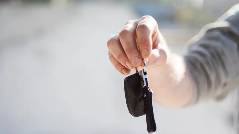 Hand holding out a car key at handover