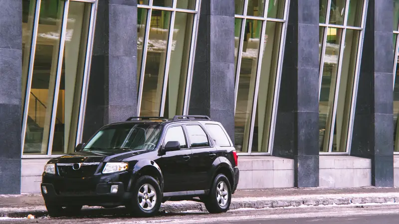 Black SUV parked outside a glass office building