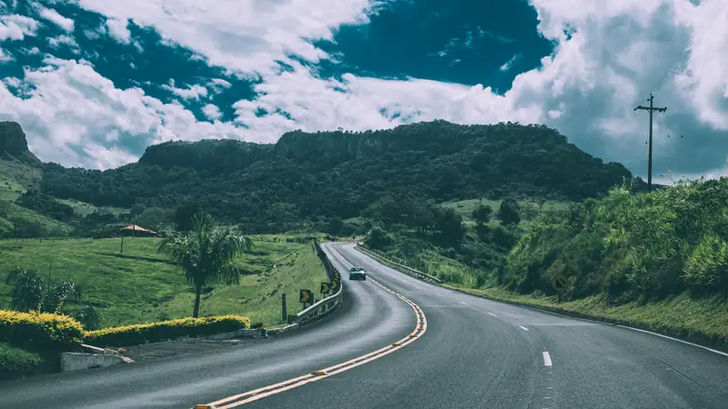 Winding two-lane road through green hills