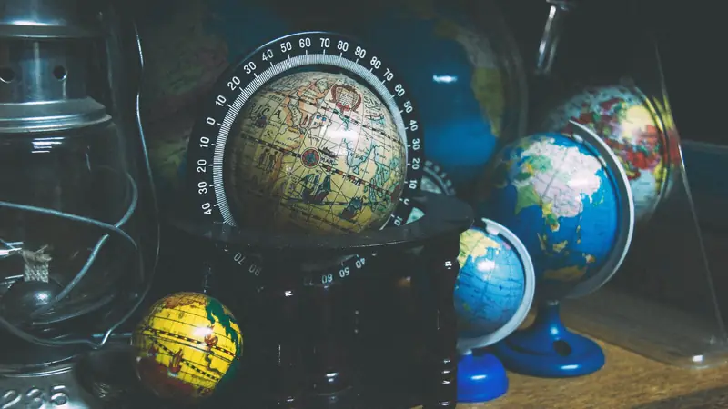 Collection of desk globes on a dark shelf
