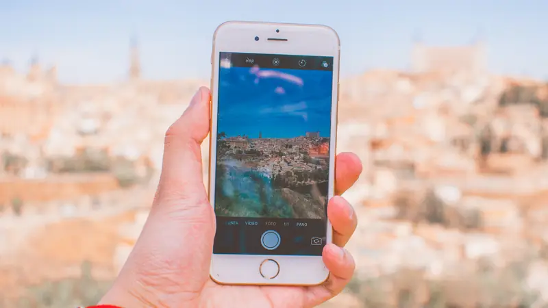 Hand holding a smartphone photographing an old town