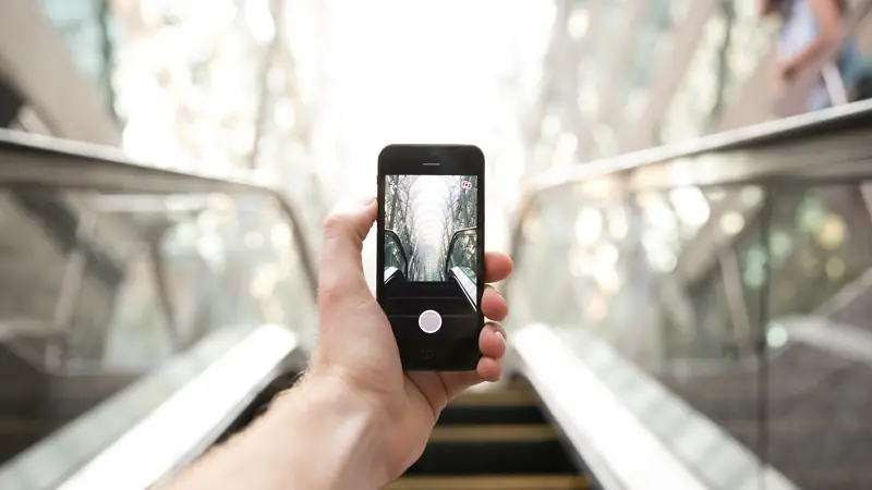 Hand holding a smartphone on an airport travelator