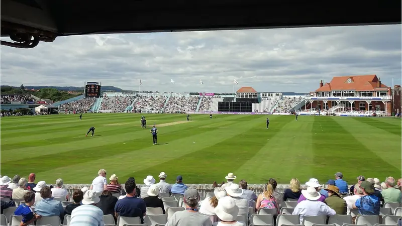 Spectators watching a cricket match at a sunlit county ground