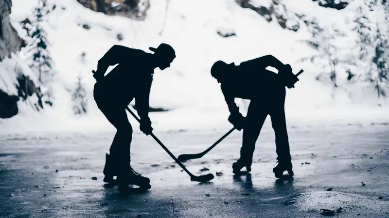 Two ice hockey players in silhouette on an outdoor rink
