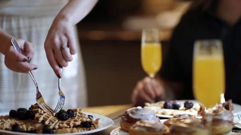 Pastries, waffles and glasses of juice served at a table