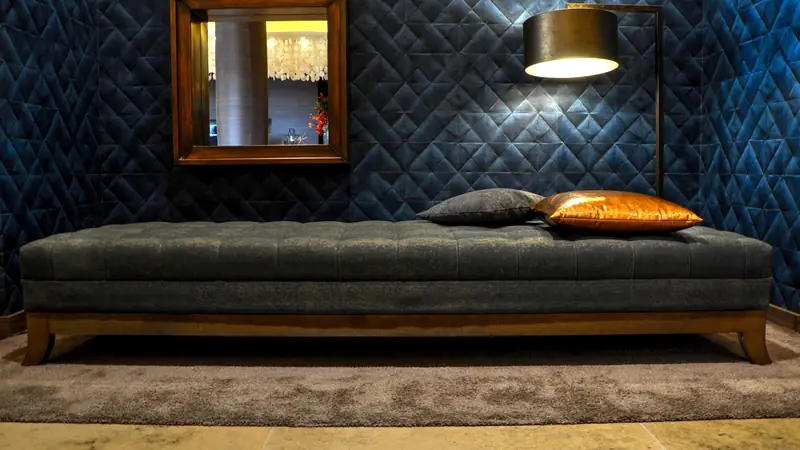 Upholstered daybed with cushions and a reading lamp in a quiet lounge
