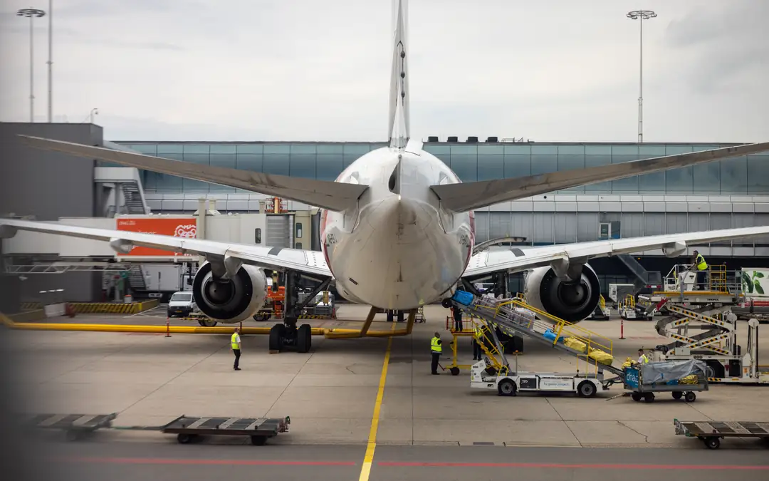 Wide-body aircraft parked at a gate with ground crew and service vehicles